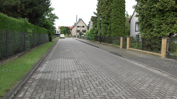 In einem Plattenbaugebiet parken zahlreiche Autos, ein Polizeiwagen steht auf der Straße