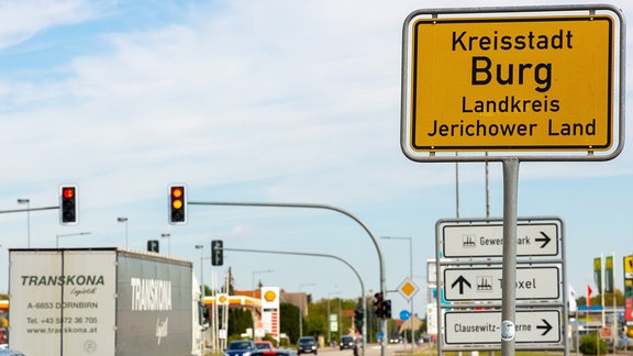 Neben einer Straße steht das Ortseingangsschild von Burg.