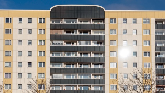 Die Sonne spiegelt sich in einem Fenster eines Wohnhochhauses.