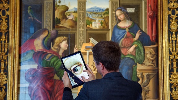 Ein Mitarbeiter schaut sich Details eines hochaufgelösten Fotos des Gemäldes "Verkündigung an Maria" im Bode-Museum auf einem Tablet an.