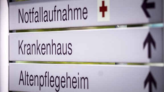 Hinweisschild vor einem Krankenhaus mit den Richtungsangaben zur Notfallaufnahme, Krankenhaus und Altenpflegeheim.