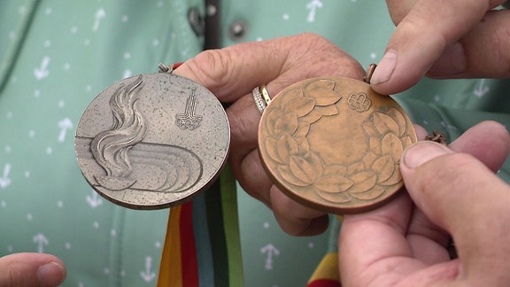 Eine silberne und eine bronzefarbene Olympia-Medaille werden in die Kamera gehalten