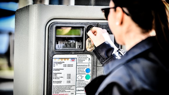 Eine Frau bezahlt am Parkautomat.