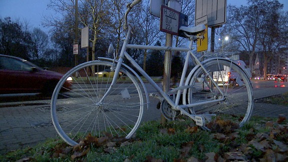 Ein weißes Fahrrad am Straßenrand