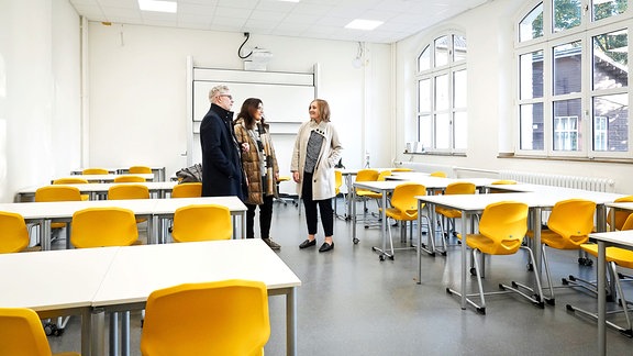 Ein Mann und zwei Frauen in einem leeren Klassenraum