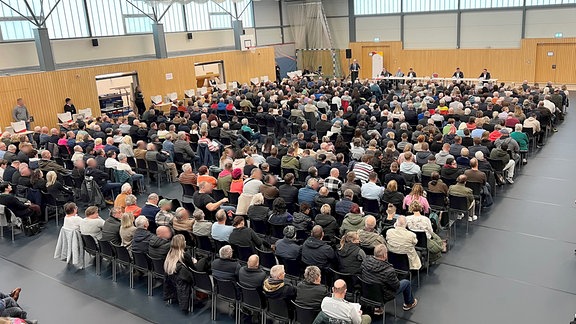 In einer Sporthalle sitzen hunderte CDU-Mitglieder auf Stühlen