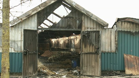 Feuerwehrmänner löschen in dichtem Rauch eine Lagerhalle.