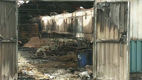 Feuerwehrmänner löschen in dichtem Rauch eine Lagerhalle.