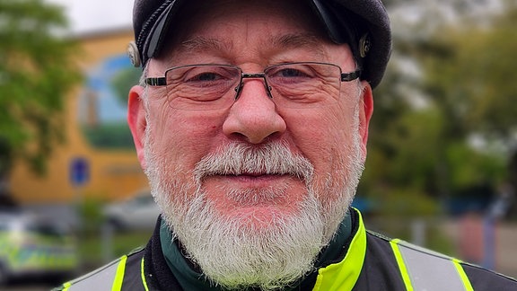 Gerd Schönfeld von der Verkerhswache Salzwedel im Porträt. Er trägt eine Warnweste und eine Schirmmütze und hat einen weißen Bart.