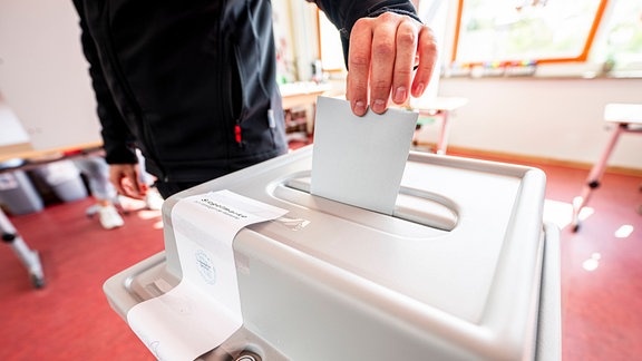 Ein Wähler wirft seinen Wahlschein in die Urne im Wahlraum.