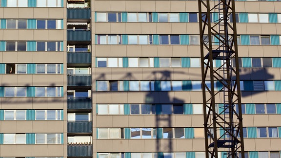 Der Schatten eines Krans wird auf ein Wohnhaus geworfen.