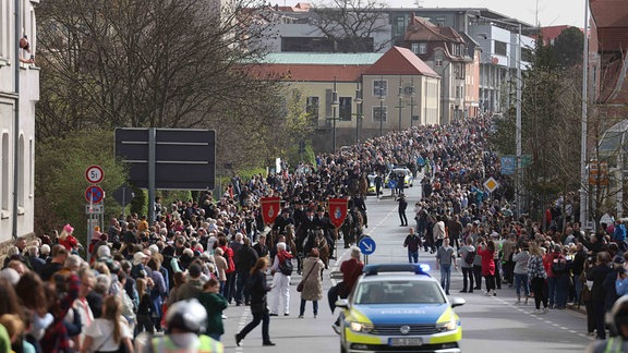 An einer Straße stehen viele Menschen.