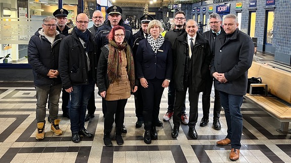 Eine Personengruppe steht in der Eingangshalle eines Bahnhofs.