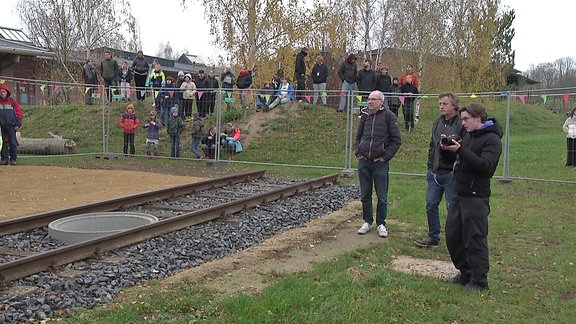 Schüler und Lehrer der Freien Waldorfschule Görlitz stehen an einem kurzen Gleisstück vor ihrer Schule in einem ehemaligen Güterbahnhof