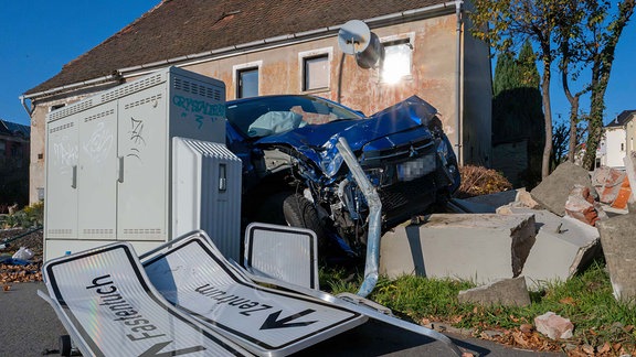 Ein verunfalltes Auto an einer zerstörten Mauer