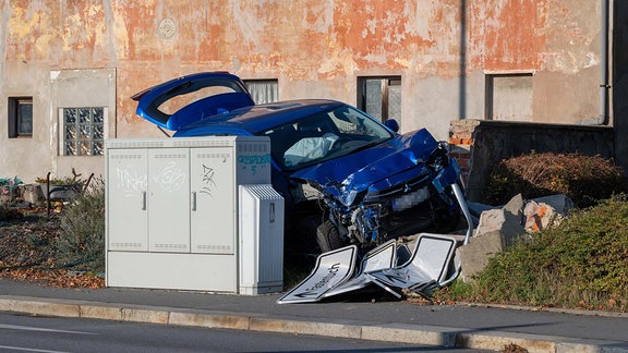 Ein verunfalltes Auto an einer zerstörten Mauer