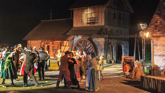 Menschen tanzen vor eine Mühle