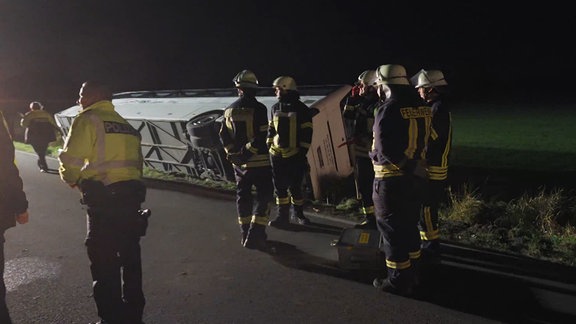 Ein Bus, der im Straßengraben liegt. Rettjungskräfte drumherum.