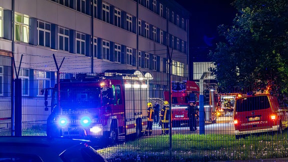 Hinter einem Stacheldrahtzaun stehen Feuerwehrautos auf dem Gelände der Erstaufnahmeeinrichtung Schneeberg.