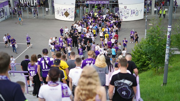 Fussballfans warten in langer Schlange am Eingang zum Stadion.