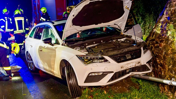 Ein Unfallwagen, dahinter Feuerwehrleute im Einsatz