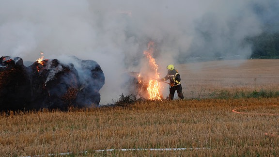 Ein Feuerwehrmann löscht Strohballen