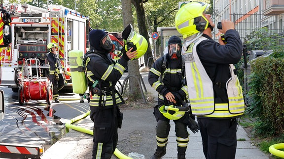 Einsatzkräfte der Feuerwehr stehen vor dem Wohnhaus.