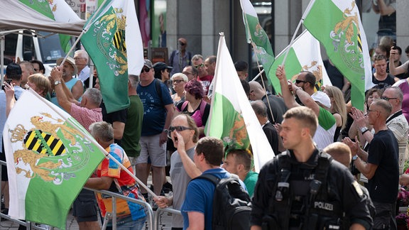 Teilnehmer einer Protestkundgebung der Partei "Freie Sachsen" stehen am Rande des Wahlkampfabschlusses der SPD in Chemnitz.