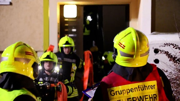 Feuerwehrleute laufen aus einem Treppenhaus.