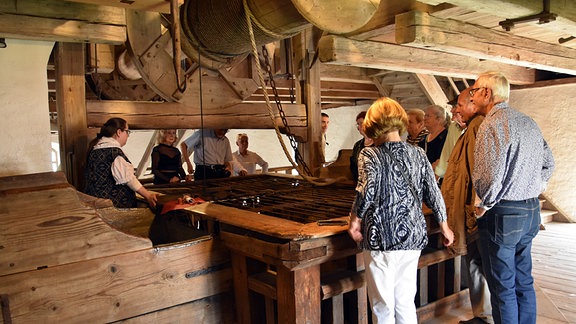 Eine Gruppe von älteren Frauen und Männern schaut in den Brunnen von Schloss Augustusburg.