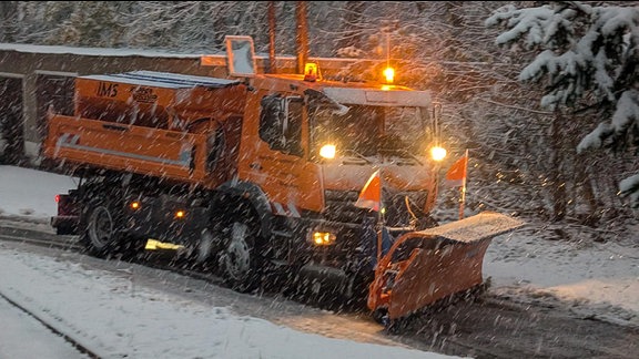 Ein Räumfahrzeug fährt durch Schneetreiben.