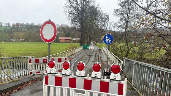 Blick über eine schmale Brücke, die für PKW komplett gesperrt ist. Nur Fußgänger dürfen drüber, zeigt ein Verkehrsschild an. 