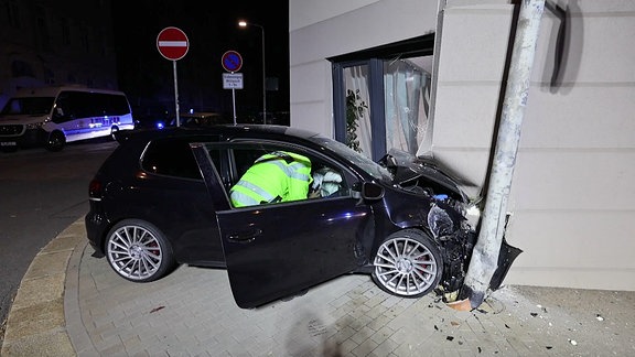 Ein dunkles Auto ist in ein helles Haus gefahren und jetzt vollkommen demoliert