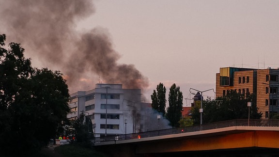 Von einer Brücke steigen an mehreren Stellen Rauchwpolken auf.