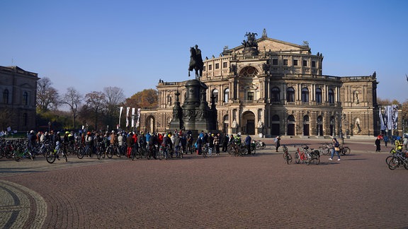 Eine Menschenmenge steht mit Fahrrädern vor der Dresdner Semperoper.