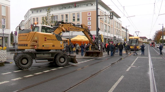 Viele Schaulustige stehen auf einer fertig ausgebauten Straße.