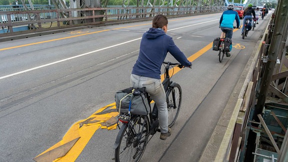 Menschen fahren auf einem Fahrradweg über eine Brücke.