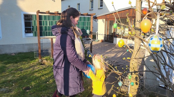 Eine Frau spielt mit ihrem Kind im Garten.