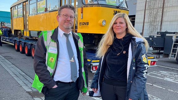 Ein Mann und eine Frau stehen vor einer Straßenbahn.