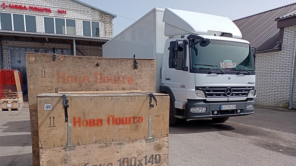 Lkw steht hinter Kisten mit kyrillscher Aufschrift "Nova Poshta"