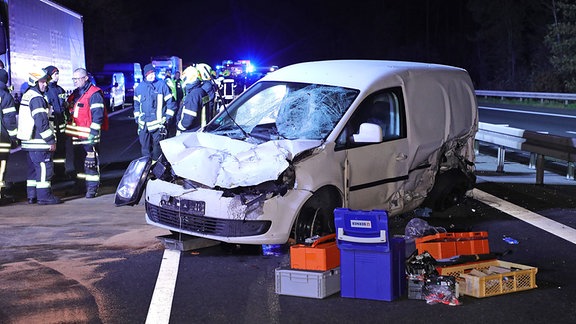 Ein demoliertes Fahrzeug steht schräg auf der Autobahn, im Hintergrund befinden sich Einsatzkräfte der Feuerwehr.