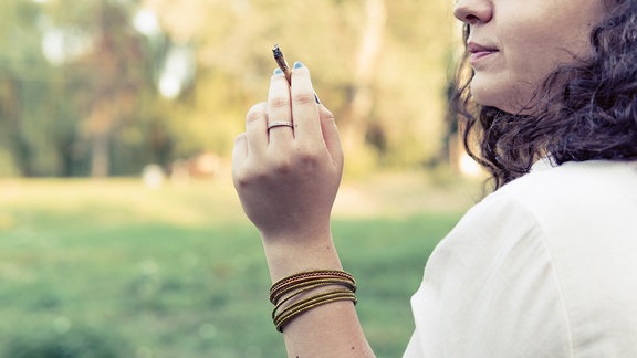 Eine Frau hält einen Joint in der Hand