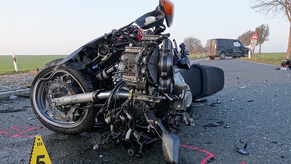 Auf einer Straße liegt ein zerstörtes Motorrad