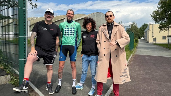 Kai Winkler, Hagen Schanze, Manja Seemann und Alexander Kovalenko neben einem Straßenschild mit der Aufschrift "European Peace Ride Straße"