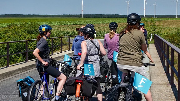 Radlerinnen auf einer Brücke in der Landschaft