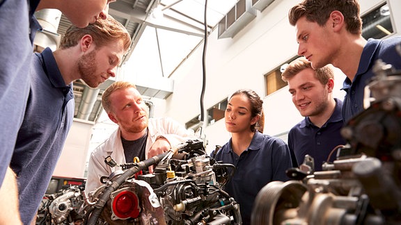 Auzbis bekommen eine Erleuterung an einem Motor.