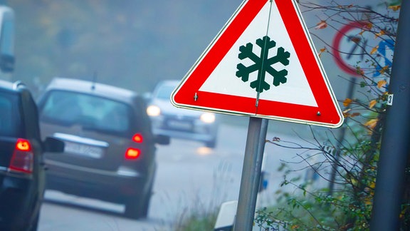 Verkehrsschild Achtung Glätte, Landstraße im Morgennebel