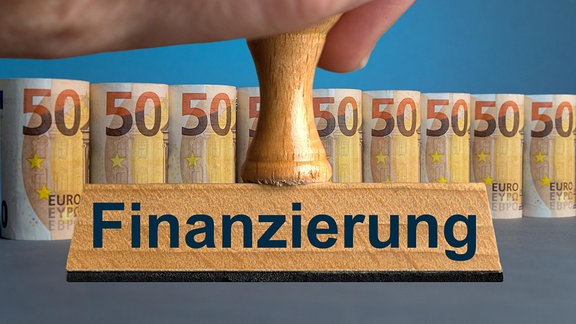 Stempel mit der Aufschrift "Finanzierung" vor aufgereihten und aufgerollten 50 Euro Scheinen