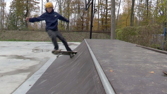 Kinder und Jugendliche fahren auf einer Skate-Anlage.