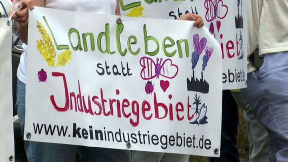 Menschen halten Protestschilder gegenn das geplante Industriegebiet bei Wiedemar hoch.